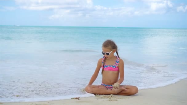 Adorable niña activa sentada en la playa de arena — Vídeos de Stock