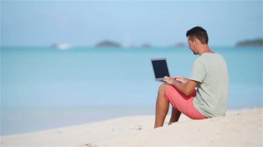 Tropik plaj tatili sırasında tabletli genç adam