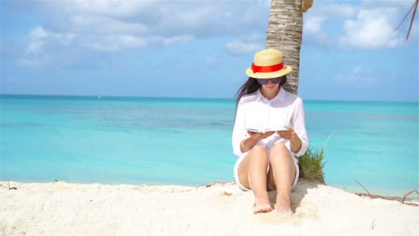 Fiatal nő olvasás könyv alatt trópusi fehér strand — Stock videók