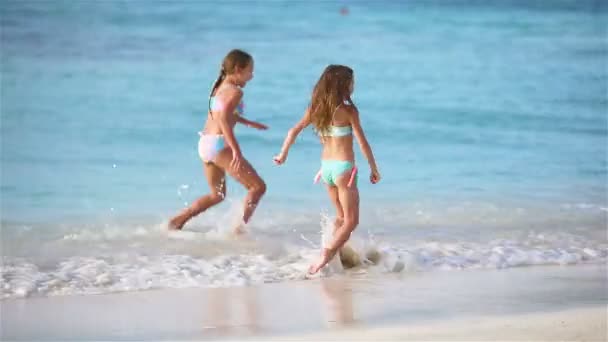 Чарівні маленькі дівчата гуляють на пляжі і розважаються разом — стокове відео