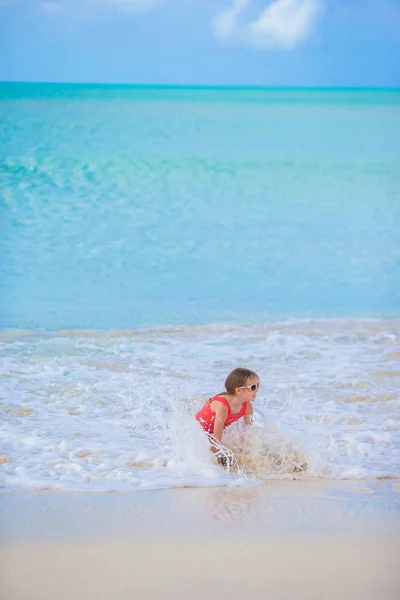 Adorable niña en la playa teniendo un montón de diversión en aguas poco profundas —  Fotos de Stock