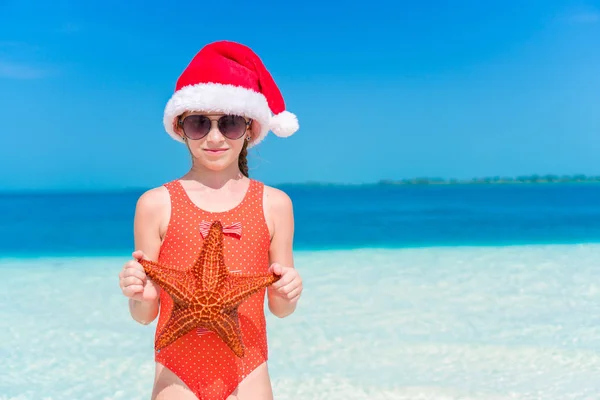 Entzückendes kleines Mädchen mit Seesternen am weißen, leeren Strand — Stockfoto