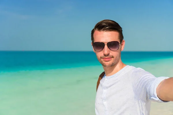 Szczęśliwy człowiek biorąc selfie na tropikalnej plaży — Zdjęcie stockowe