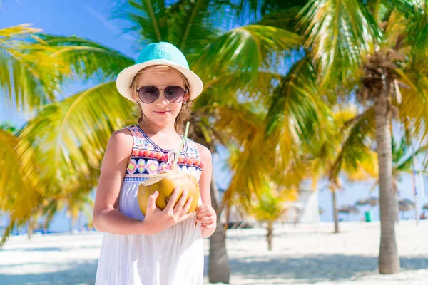 Kleines glückliches Mädchen mit großer Kokosnuss am Strand — Stockfoto