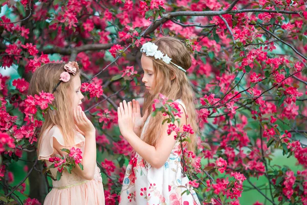 Чарівні маленькі дівчата в квітучому саду яблуні на весняний день — стокове фото