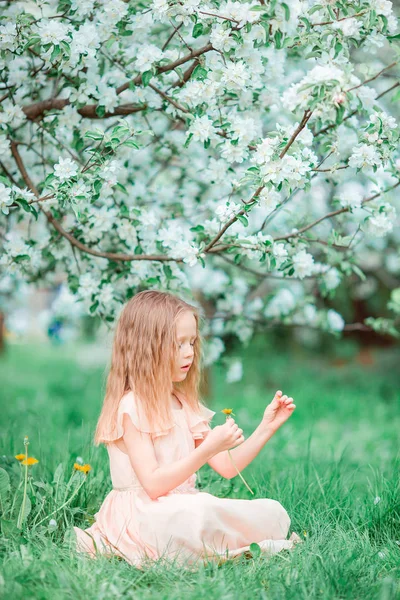 Очаровательная маленькая девочка наслаждается весенним днем в цветущем яблочном саду — стоковое фото