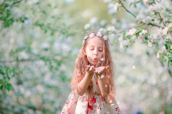 春の日に愛らしい小さな少女咲く桜木の庭 — ストック写真