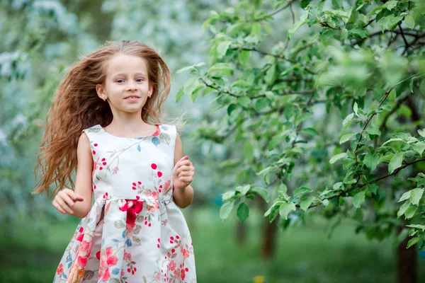 Bahar günü çiçek açan elma bahçesinde sevimli küçük bir kız. — Stok fotoğraf