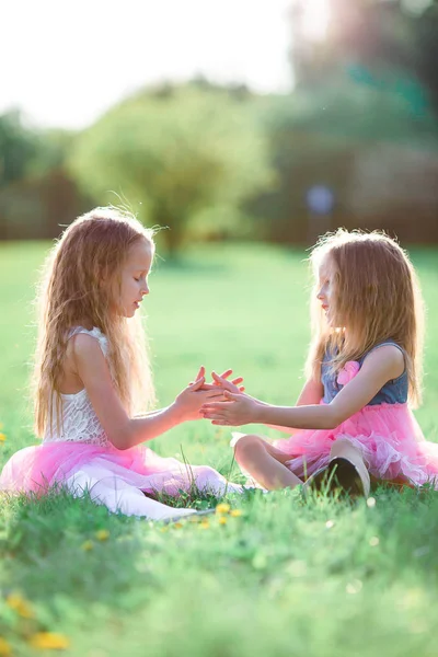 Adorable little girls on spring day outdoors sitting on the grass — Stock Photo, Image