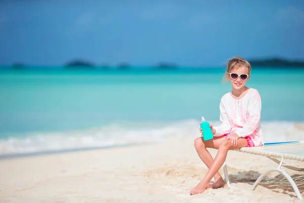 Hermoso niño con botella de crema solar en la playa tropical —  Fotos de Stock