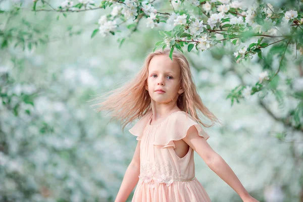 Bedårande liten flicka i blommande körsbär träd trädgård vårdag — Stockfoto