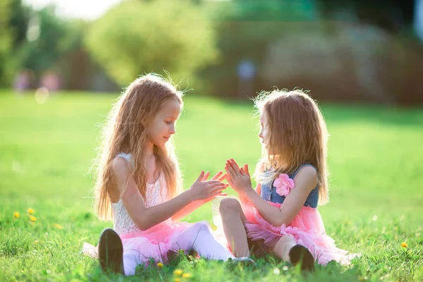 Adorable little girls on spring day outdoors sitting on the grass — Stock Photo, Image