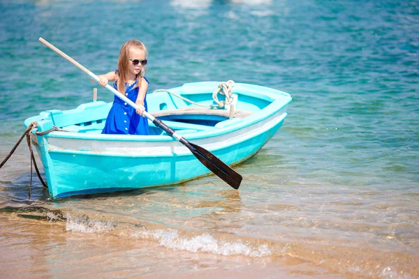 Kleines Mädchen in blauem Boot in der griechischen Meeresbucht — Stockfoto