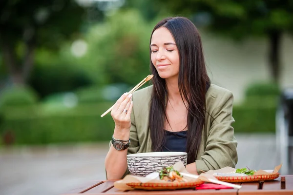 Junge Frau isst Nudeln zum Mitnehmen auf der Straße — Stockfoto
