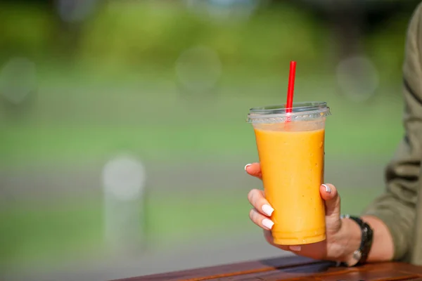 Mango smoothie w szklance w kobiecej ręce zamknij — Zdjęcie stockowe