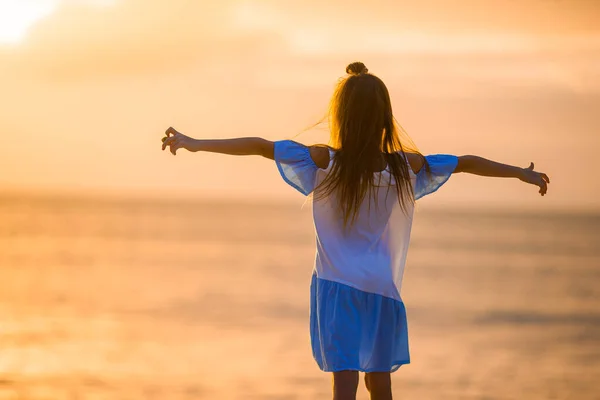 Bedårande glad liten flicka promenader på stranden vid solnedgången. — Stockfoto