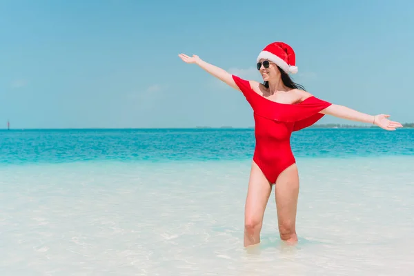 Young woman in Santa Hat walking spread her hands on white sandy beach — Stock Photo, Image