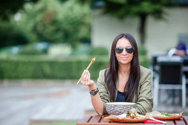 Młoda kobieta jedzenie wziąć od makaron na ulicy — Zdjęcie stockowe
