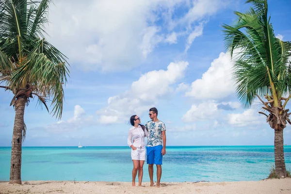 在加勒比海的热带海滩上散步的年轻夫妇，他们带着白沙和碧绿的海水 — 图库照片