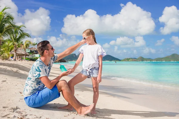 Genç baba sahildeki kızına güneş kremi sürüyor. Güneş koruması — Stok fotoğraf