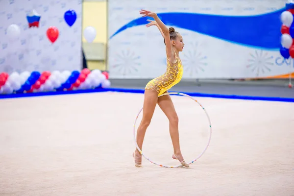 Красивая маленькая гимнастка на ковре на соревнованиях — стоковое фото