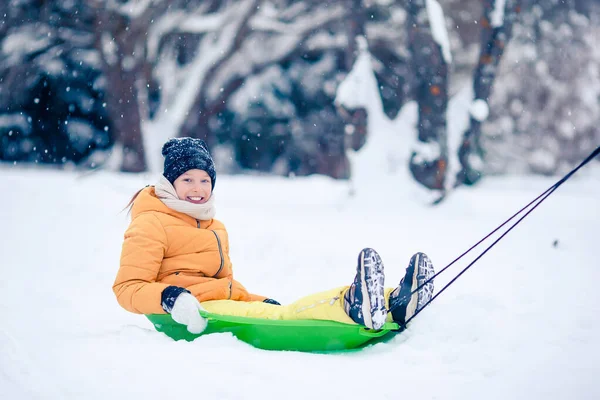 Sevimli küçük mutlu kız kışın karlı bir günde kızakla kayıyor. — Stok fotoğraf