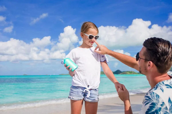 Giovane padre che applica la crema solare al naso della figlia sulla spiaggia. Protezione solare — Foto Stock