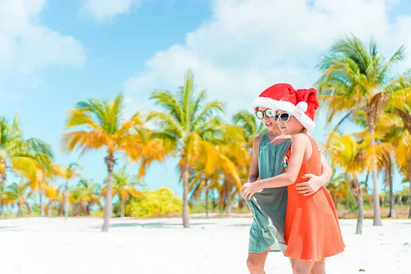 Piccole ragazze adorabili a Babbo Natale cappelli durante le vacanze al mare divertirsi insieme — Foto Stock