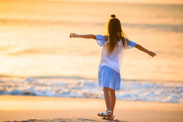 Bedårande glad liten flicka promenader på stranden vid solnedgången. — Stockfoto