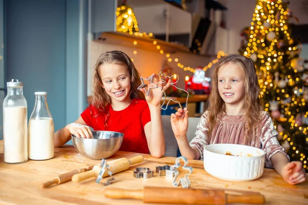 Niñas haciendo casa de jengibre de Navidad en la chimenea en la sala de estar decorada. — Foto de Stock