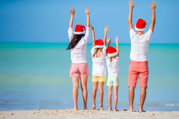 Glückliche Familie in roten Weihnachtsmützen an einem tropischen Strand feiert Weihnachtsurlaub — Stockfoto