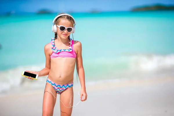 Bambina con le cuffie sulla spiaggia — Foto Stock