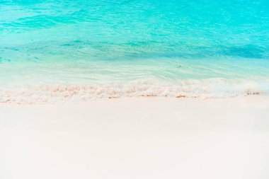 Karayip adada beyaz kum, turkuaz okyanus su ve mavi gökyüzü ile pastoral tropikal plaj