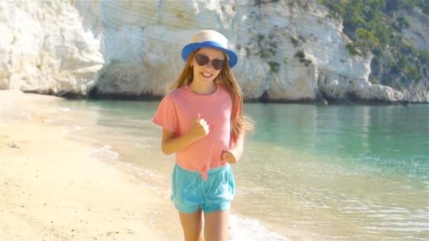 Милая маленькая девочка на пляже во время летних каникул — стоковое видео