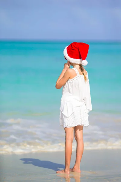 Adorable little girl in Santa hat on tropical beach — Stock Photo, Image