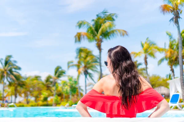 Piękna młoda kobieta relaksująca się w basenie. Dziewczyna w czerwonym bikini w odkrytym basenie w luksusowym hotelu — Zdjęcie stockowe