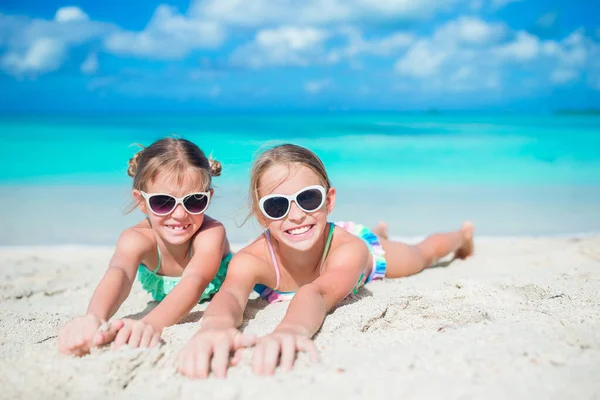 Two little happy girls have a lot of fun at tropical beach playing together  with sand Stock Photo by ©d.travnikov 183332532