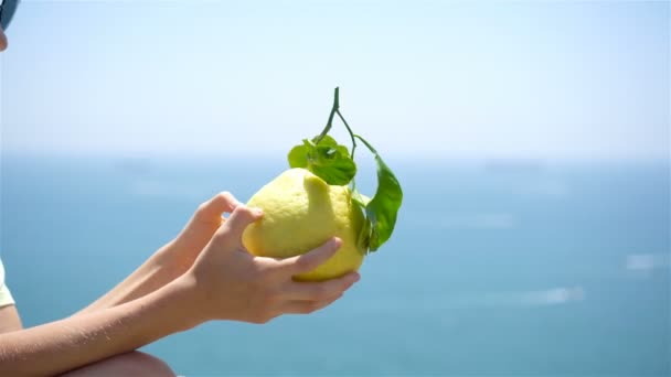 Великий жовтий лимон в руці на фоні середземного моря і неба . — стокове відео
