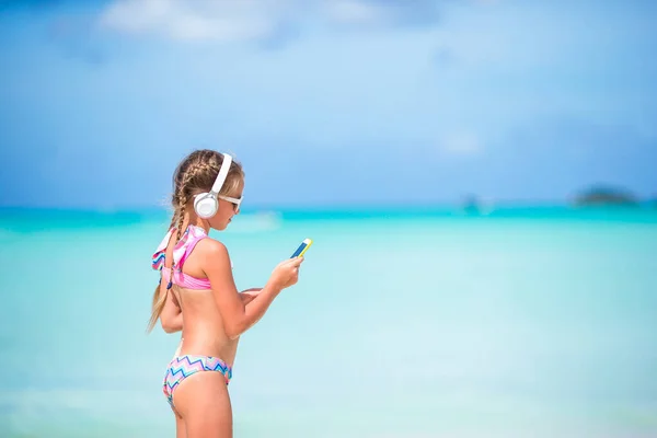 Klein schattig meisje luisteren muziek achtergrond zee — Stockfoto