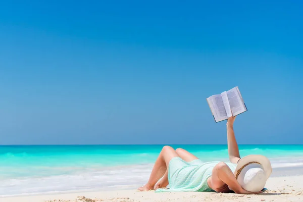Donna con libro sulla spiaggia sdraiata — Foto Stock