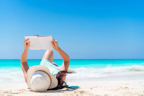 Donna con libro sulla spiaggia sdraiata — Foto Stock