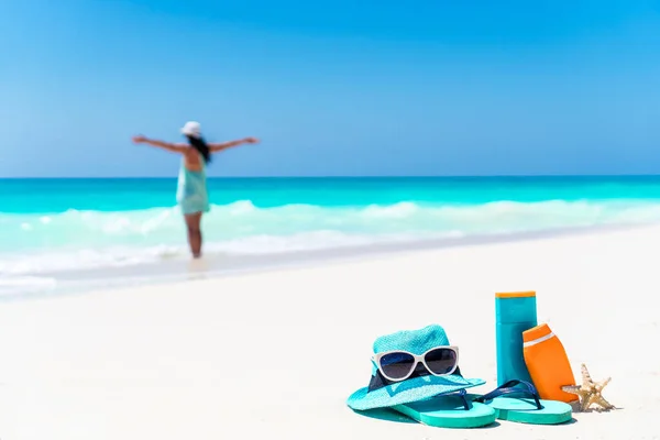Suncream şişe, güneş gözlüğü, flip flop beyaz kum zemin okyanusta — Stok fotoğraf
