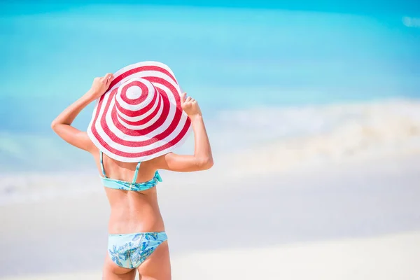 Adorable niña en sombrero rojo grande caminando a lo largo de la playa del Caribe de arena blanca —  Fotos de Stock