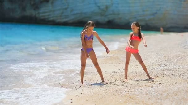 Pequenas meninas engraçadas felizes se divertir muito na praia tropical jogando juntos. Dia ensolarado com chuva no mar — Vídeo de Stock