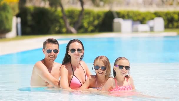 Familia feliz de cuatro en la piscina al aire libre — Vídeos de Stock