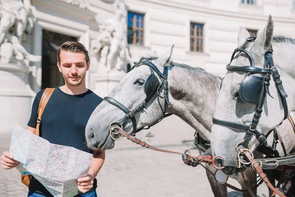 Homem turista com um mapa da cidade e mochila na Europa rua. Garoto caucasiano olha com mapa da cidade europeia . — Fotografia de Stock