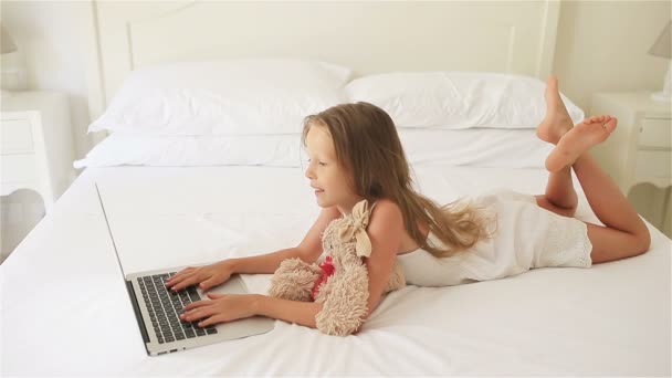 Милая маленькая девочка делает домашнее задание на ноутбуке — стоковое видео