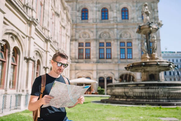 Homem turista com um mapa da cidade e mochila na Europa rua. Garoto caucasiano olha com mapa da cidade europeia . — Fotografia de Stock