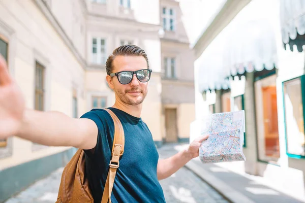 Man turist med en stadskarta och ryggsäck i Europa street. Kaukasiska pojke ser med karta över europeisk stad. — Stockfoto