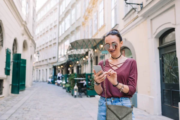 Женщина разговаривает на смартфоне в городе. Молодой привлекательный турист на открытом воздухе в итальянском городе — стоковое фото